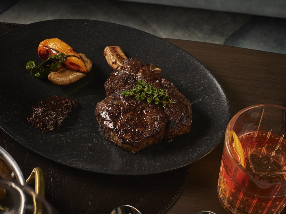 Perfectly cooked Cowboy Ribeye paired with an Old Fashioned at Crown Block, a downtown Dallas steakhouse.