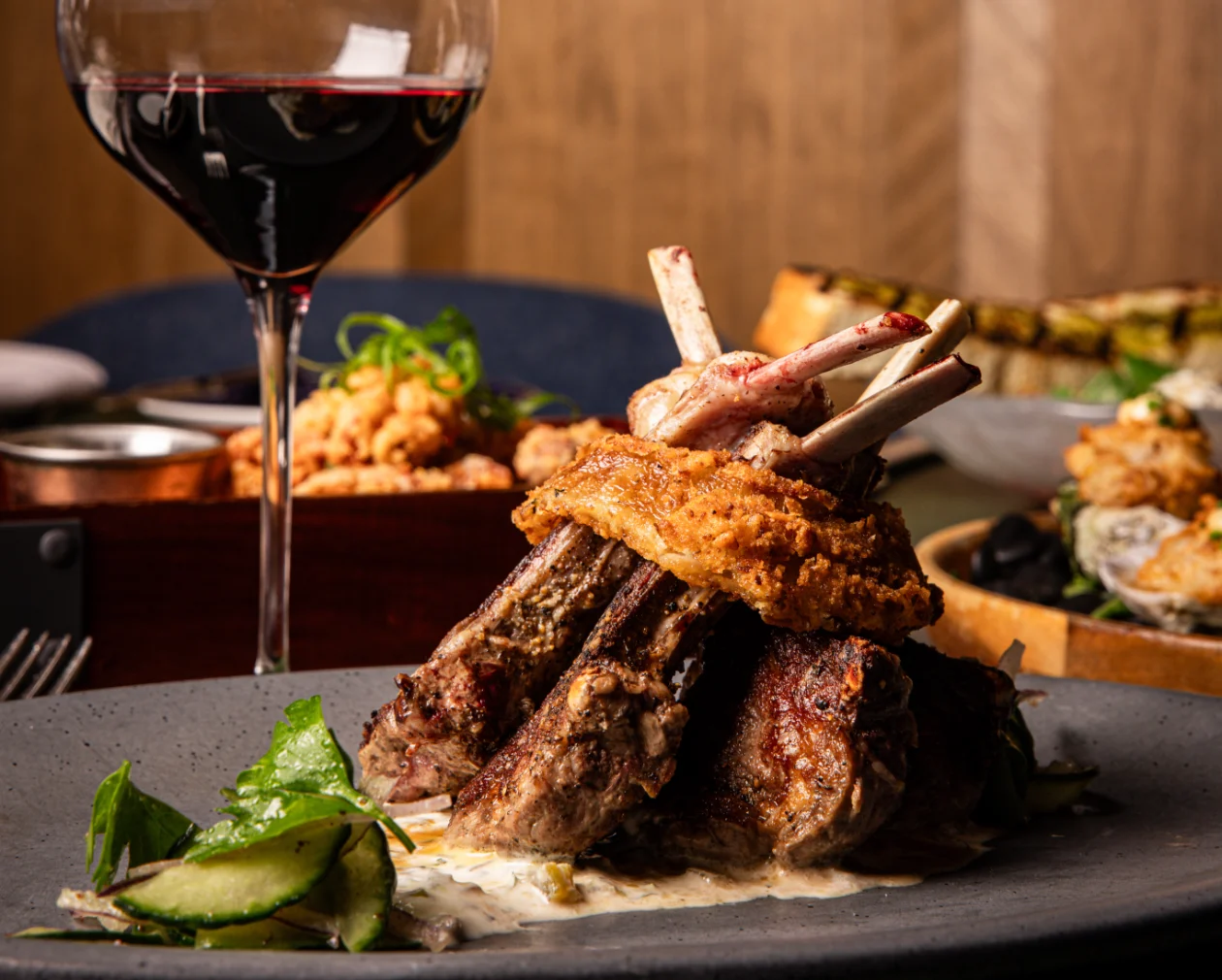 Crispy onion ring wrapped around Australian Lamb Rack with a glass of red wine at Crown Block, Michelin Recommended Steakhouse in downtown Dallas.