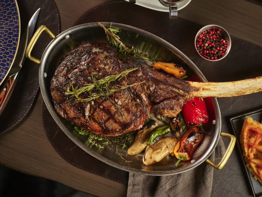 Bone-In Tomahawk steak served at Crown Block Dallas Steakhouse with rare steaks.